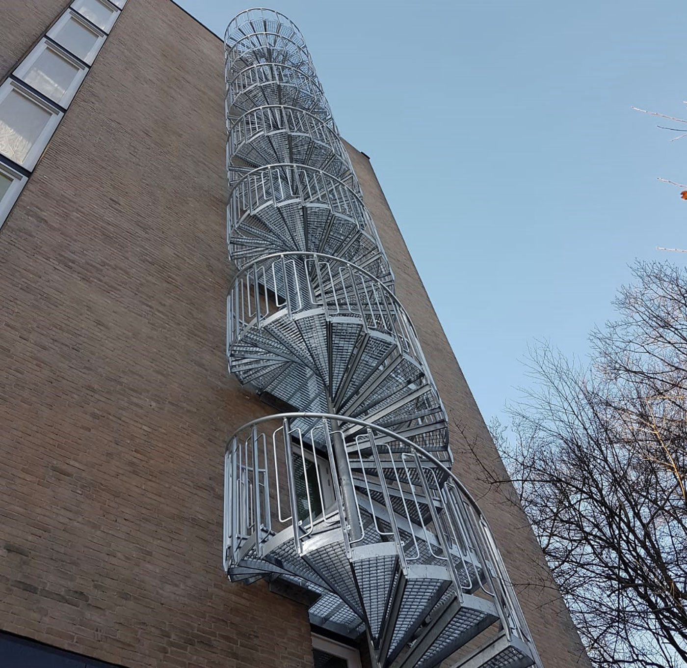 Spiral staircase outdoors with steps of grating and childsafe railing