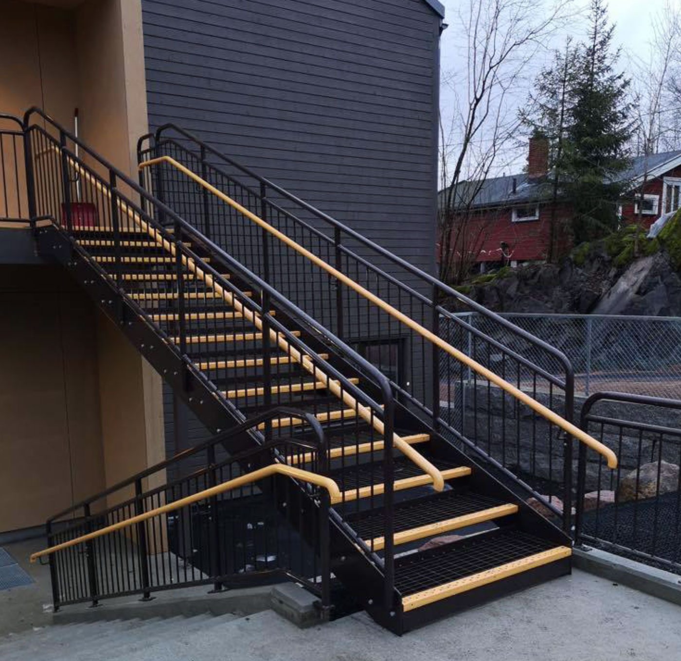 Pulverbeschichtete gerade Treppe mit Gitterroststufen und innerem Handlauf aus Holz