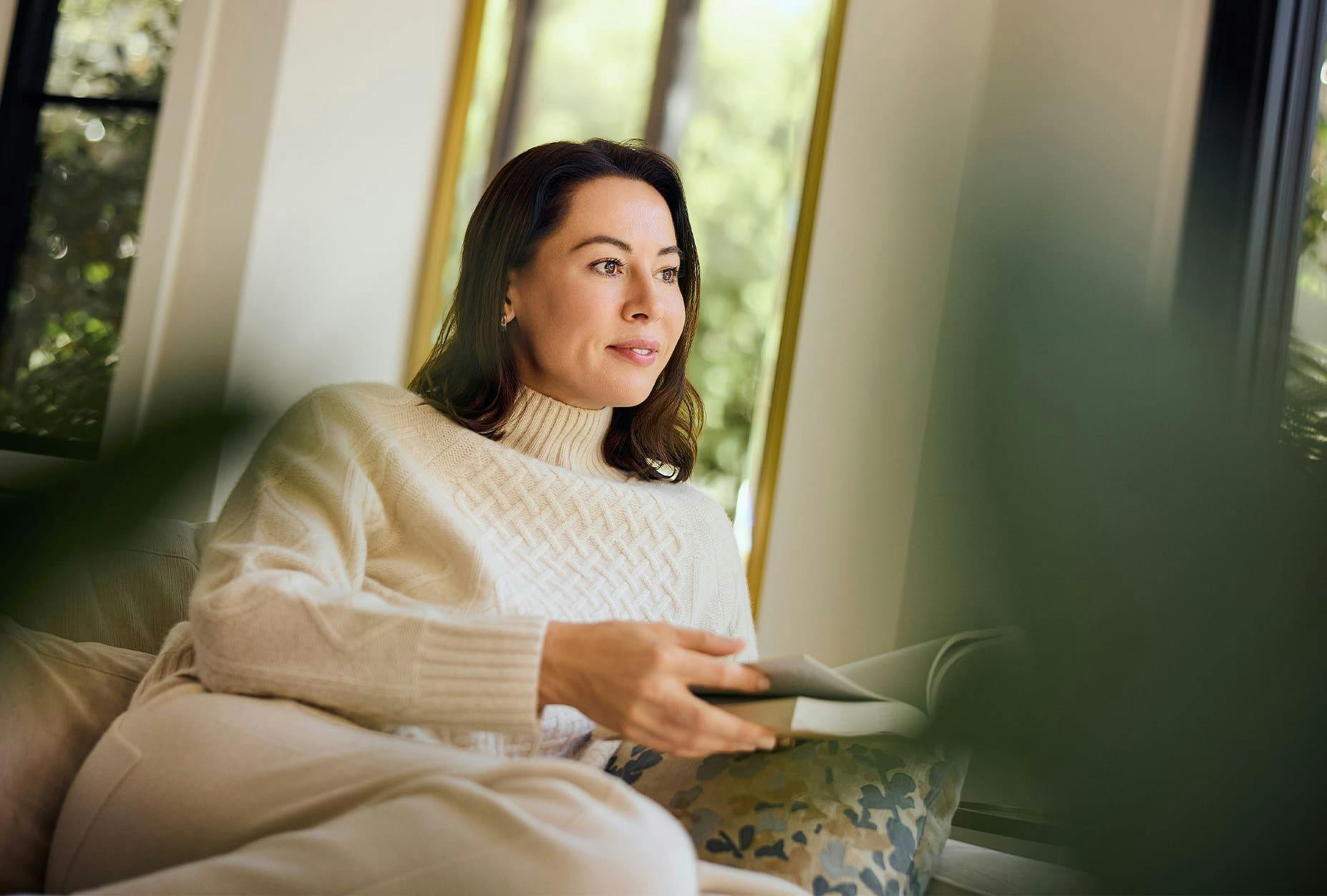 woman sitting on couch with book open in her hands