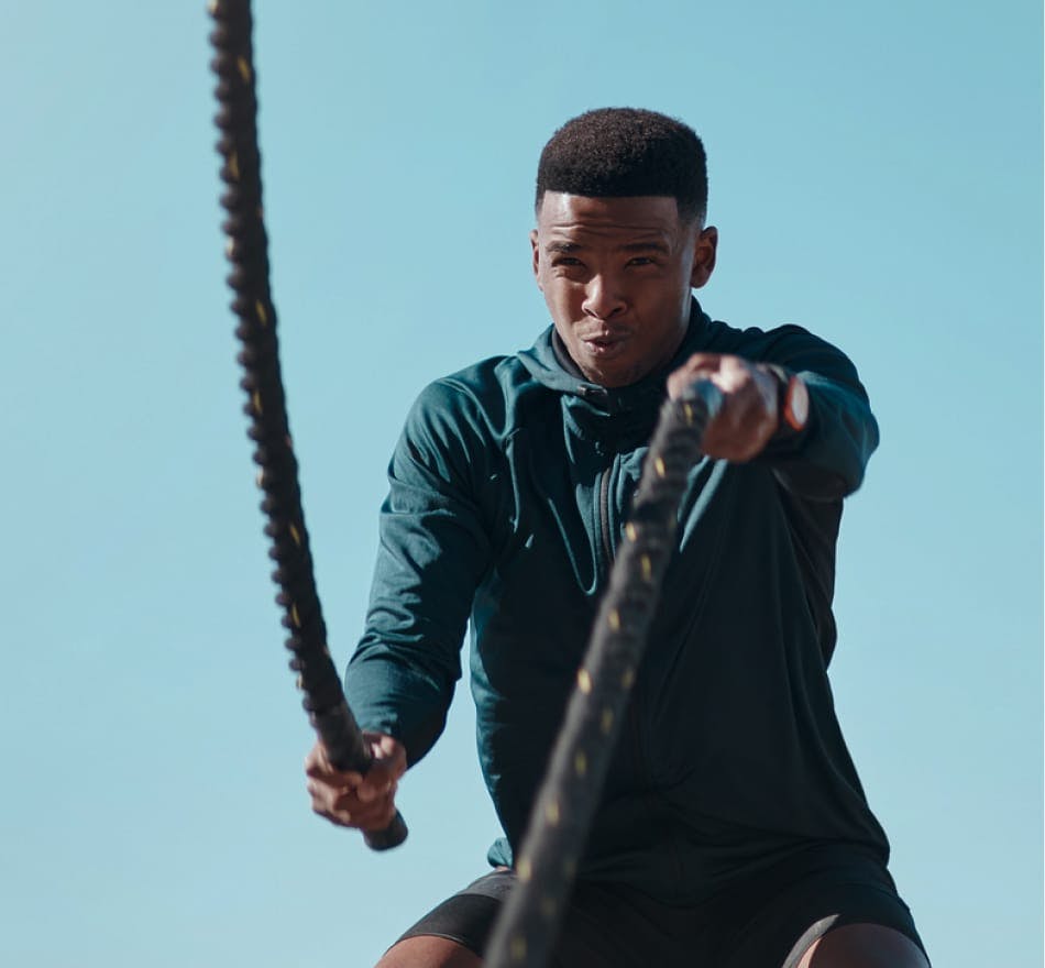 man doing battle rope exercise in long sleeve shirt and shorts