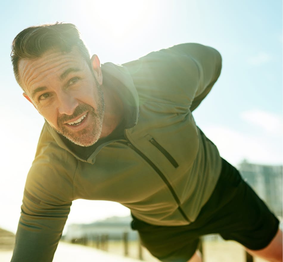 man doing one armed push-up in long sleeved jacket and shorts