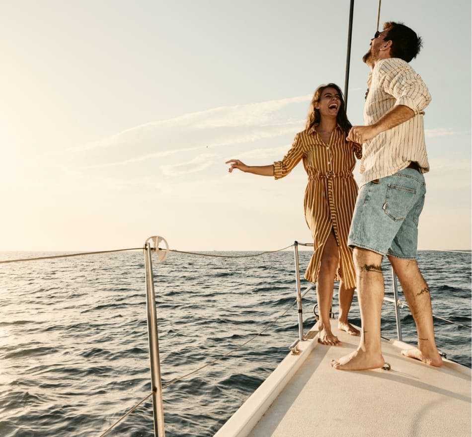 man and woman standing at front of a boat laughing