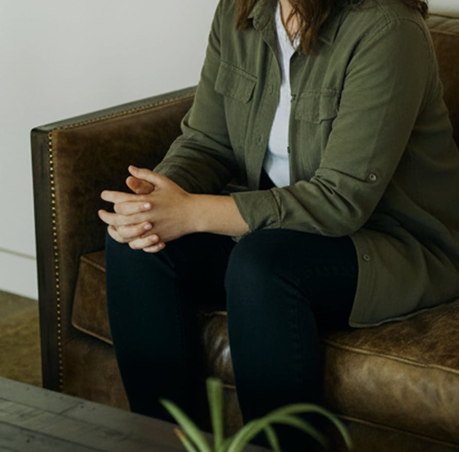 client sitting on couch holding hands in lap