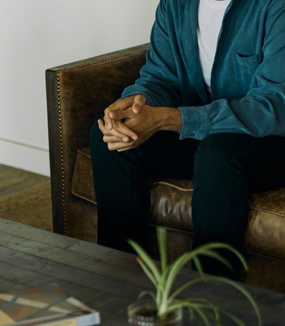 person sitting on couch with hands clasped