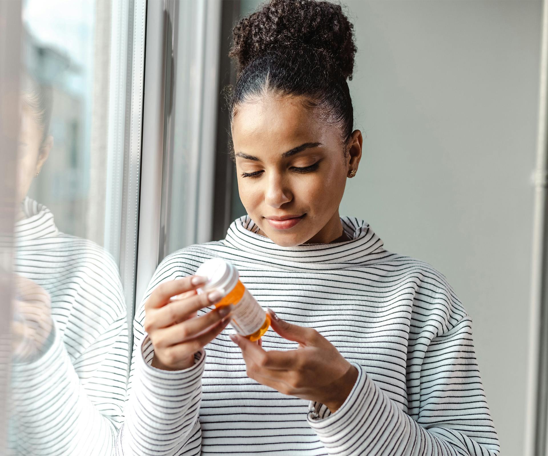 woman looking at pill bottle