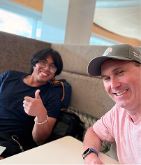 2 people smiling in an office. one is giving a thumbs up