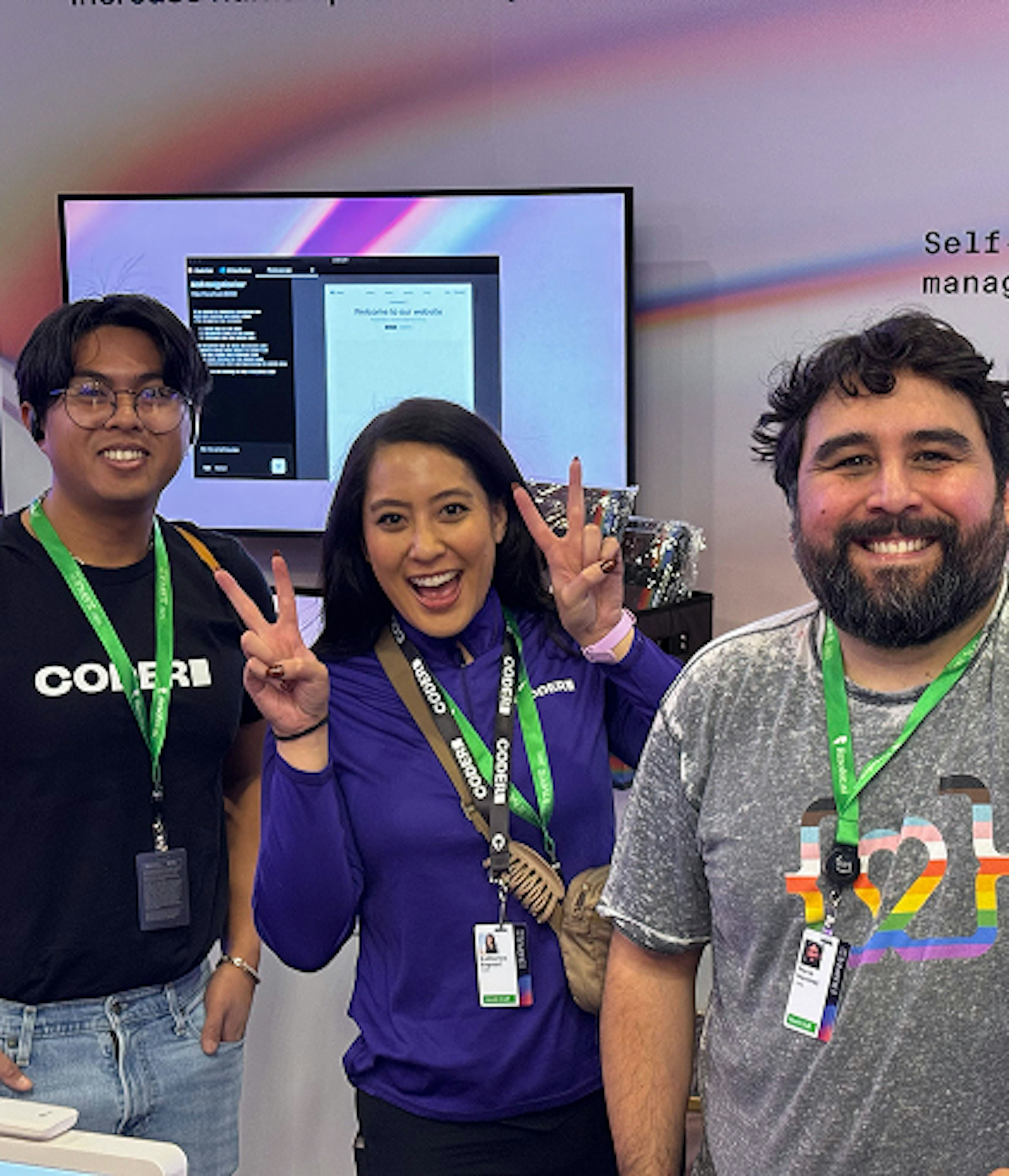 3 people smiling wearing green lanyards at a Coder event