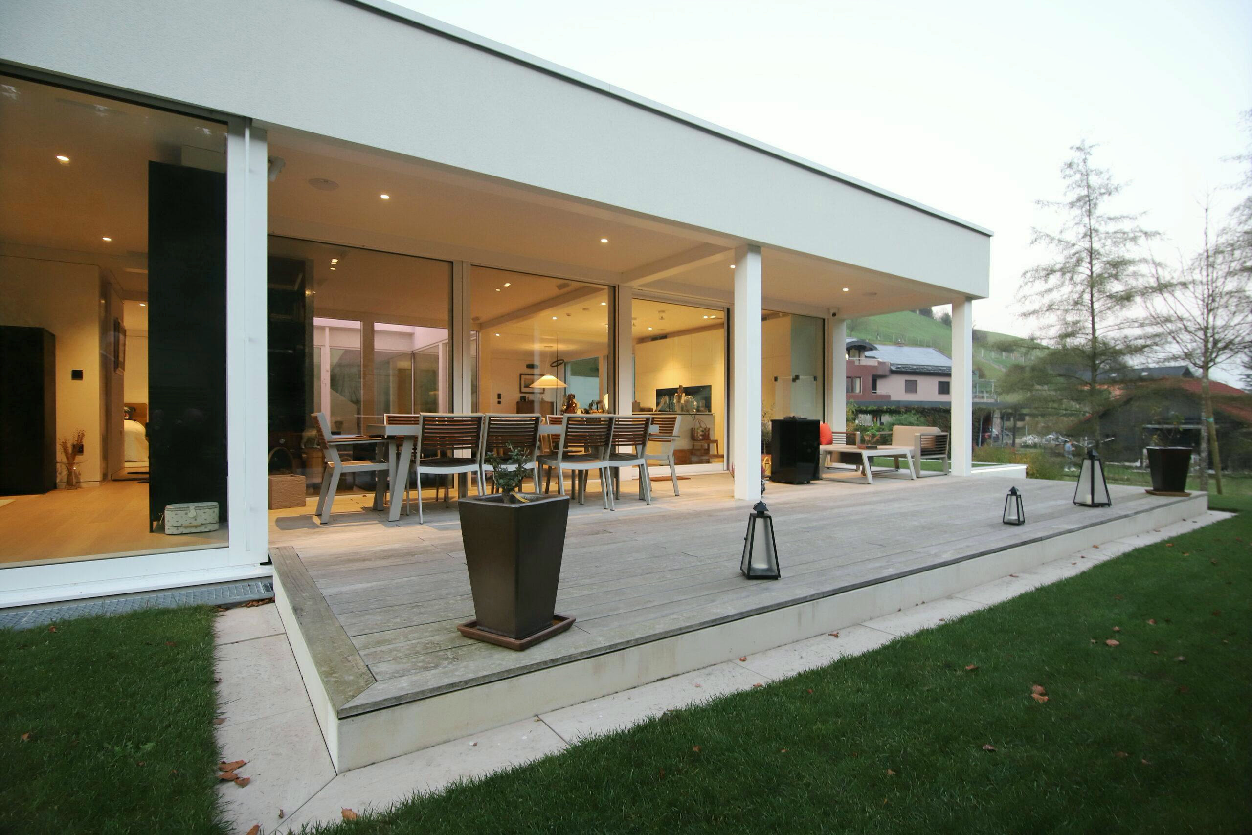 Covered terrace with a dining area beside the glazed façade
