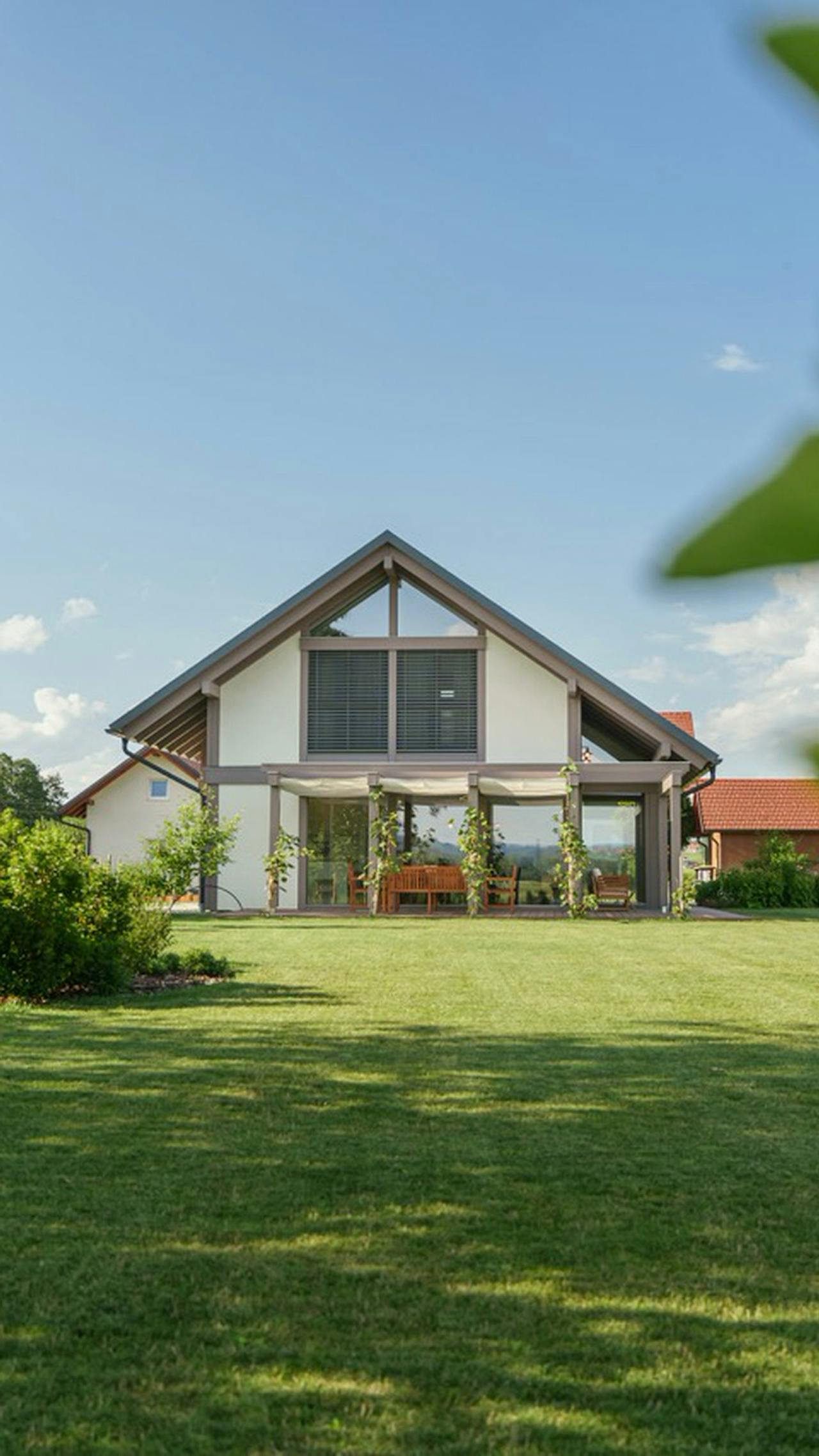 Haus mit Satteldach und verglastem Wohnbereich zum grünen Garten