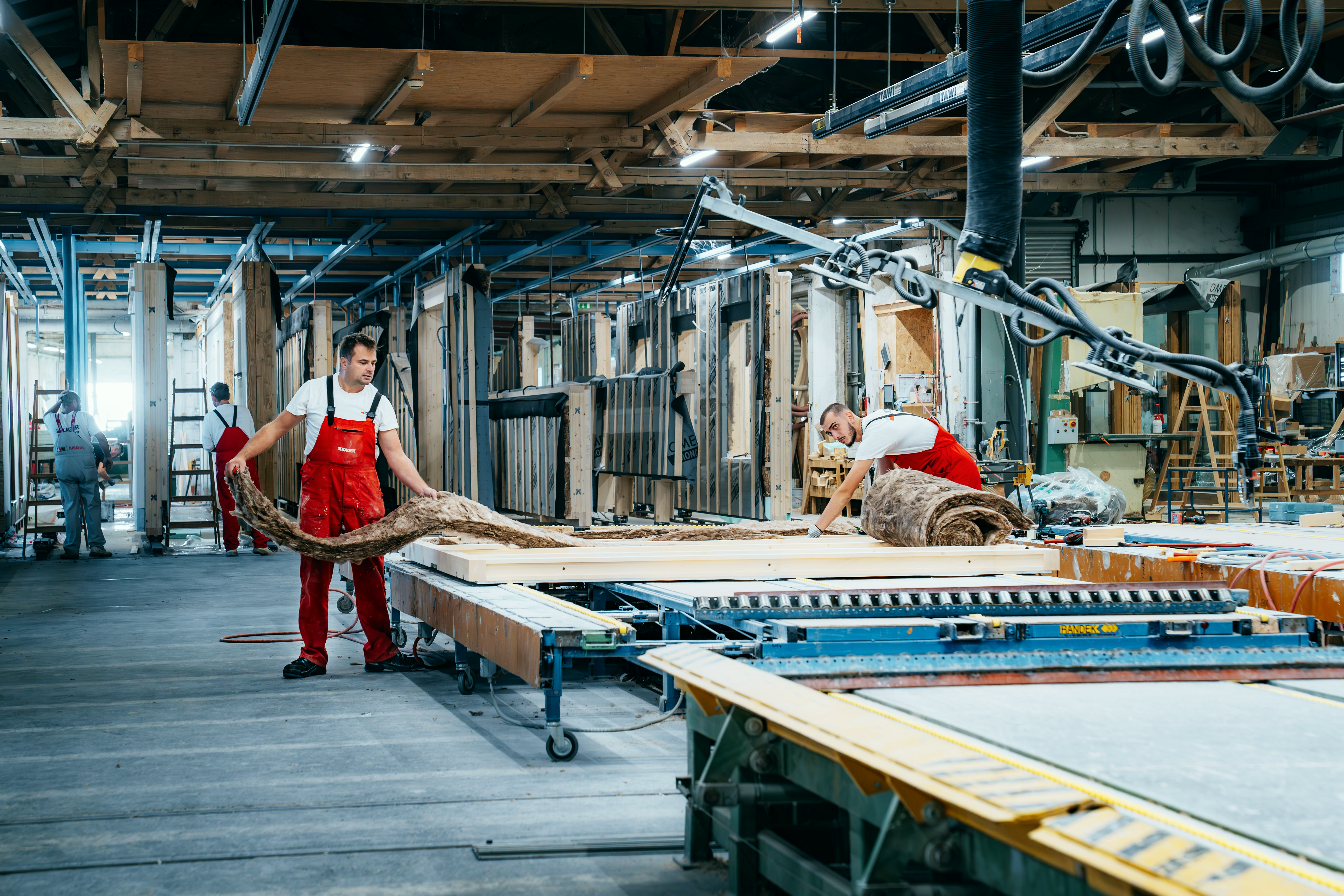 Craftspeople working together to fit insulation into a wall element