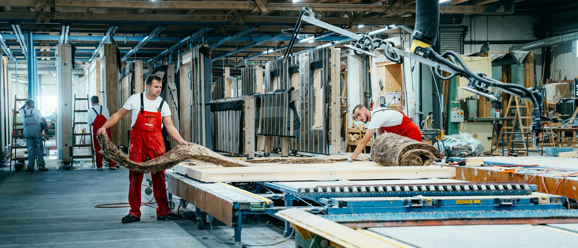 Zusammenarbeit der Fachkräfte beim Einbau der Dämmung in ein Wandelement