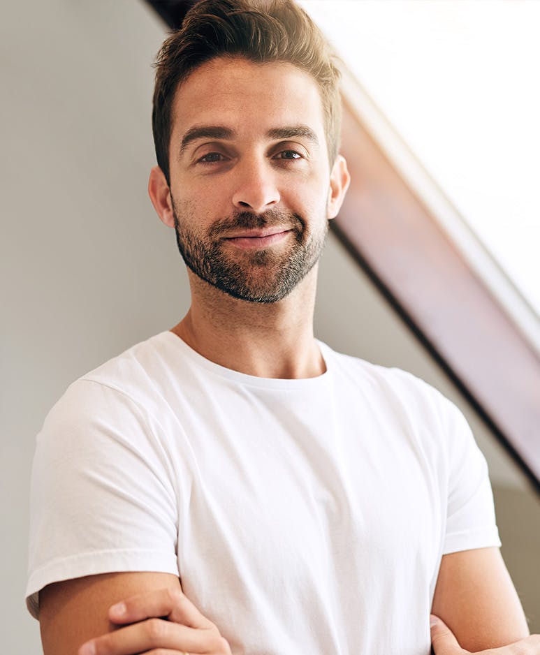 Young man smiling while standing with arms crossed