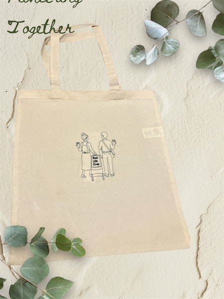 Embroidered bag with man and woman carrying a cart and holding coffee mugs