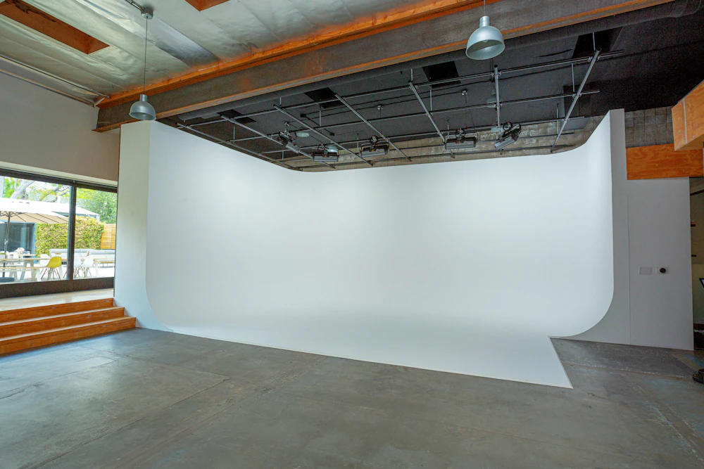 the white cyclorama studio space with lighting equipment and seating