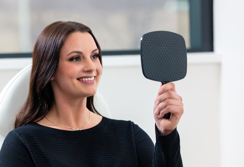 Woman looking in a hand-held mirror