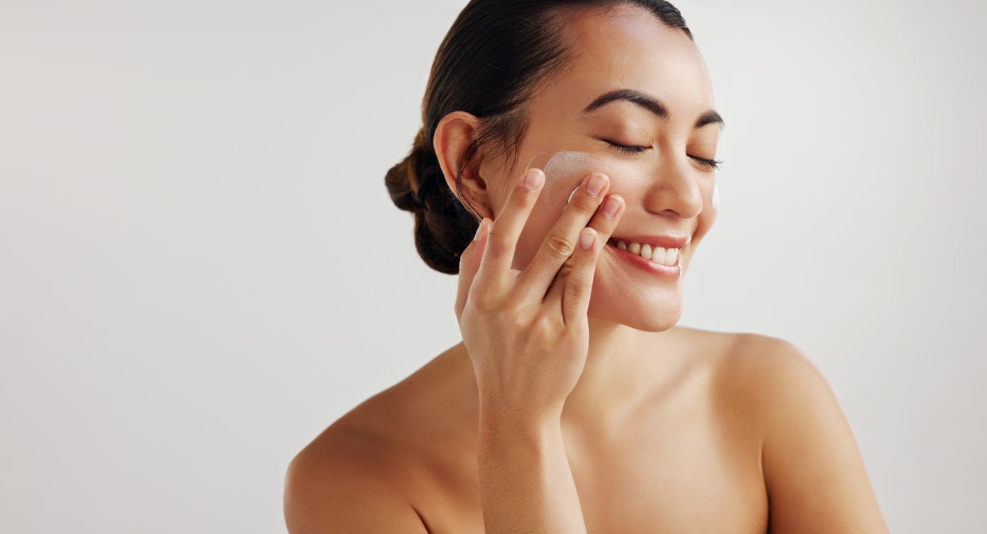 Smiling woman rubbing product on her face