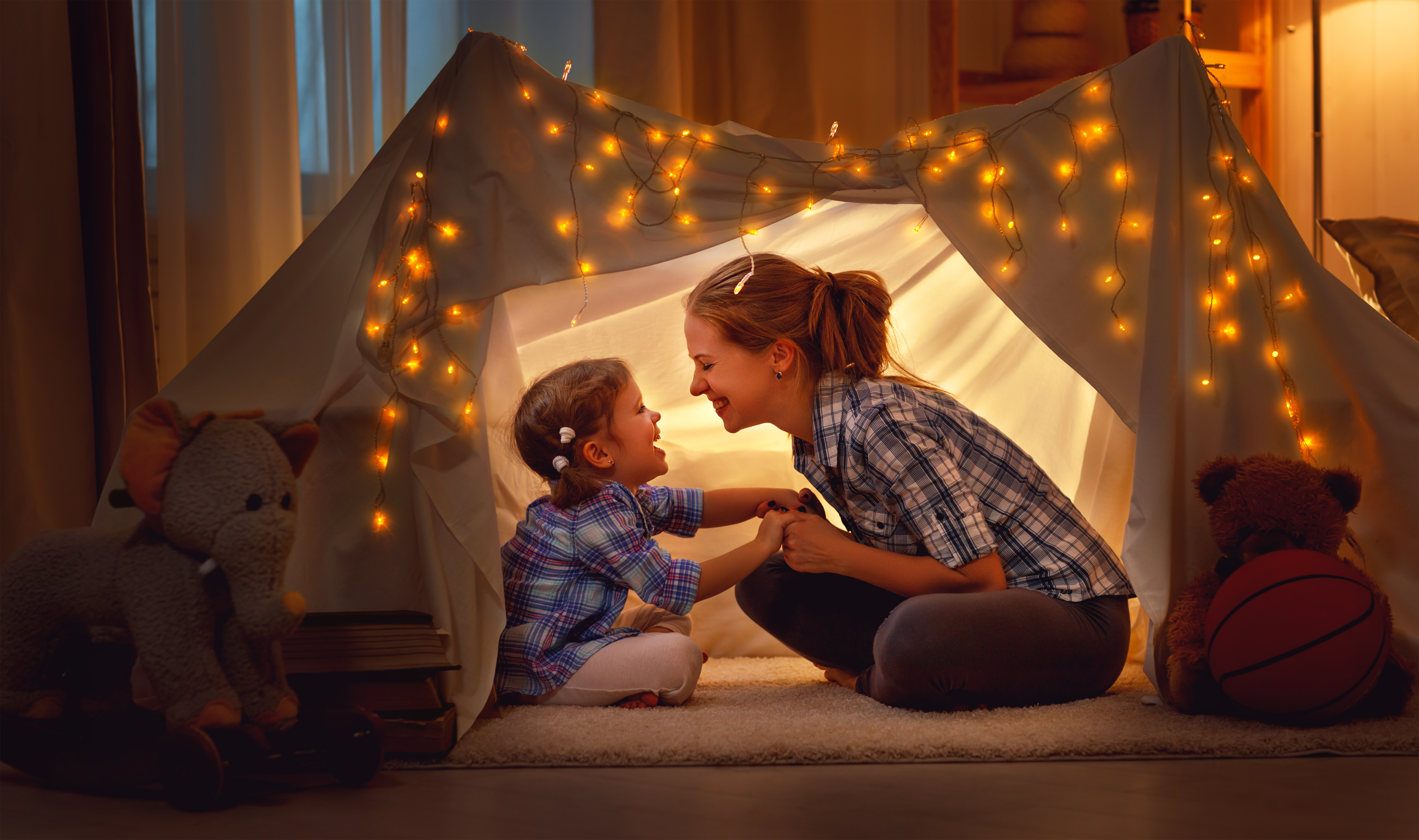 Eine Mutter die mit ihrer Tochter in einem Zeit, in einem Zimmer, sitzt und freudig mit ihr spielt. Sorgen auch Sie mit dem Edelmetall-Kindersparplan von Golden Gates, für eine sorgenfreie Zukunft.