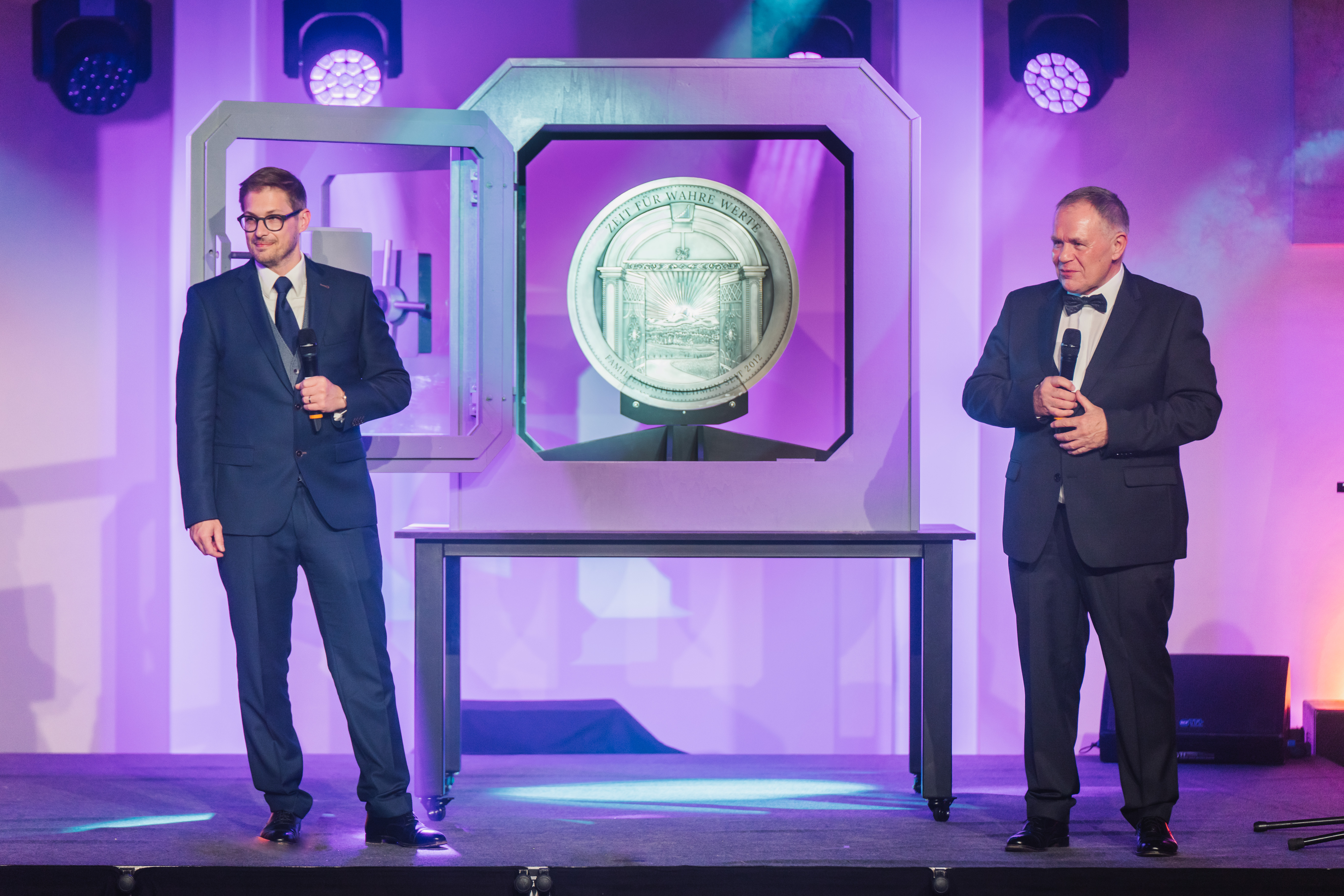 Auf der Tribüne stehen die Gründer der Golden Gates Edelmetalle AG, Herbert und Constantin Behr, und stellen die 100.000 Euro Silbermedaille vor. Angefertigt von der Firma Geiger.