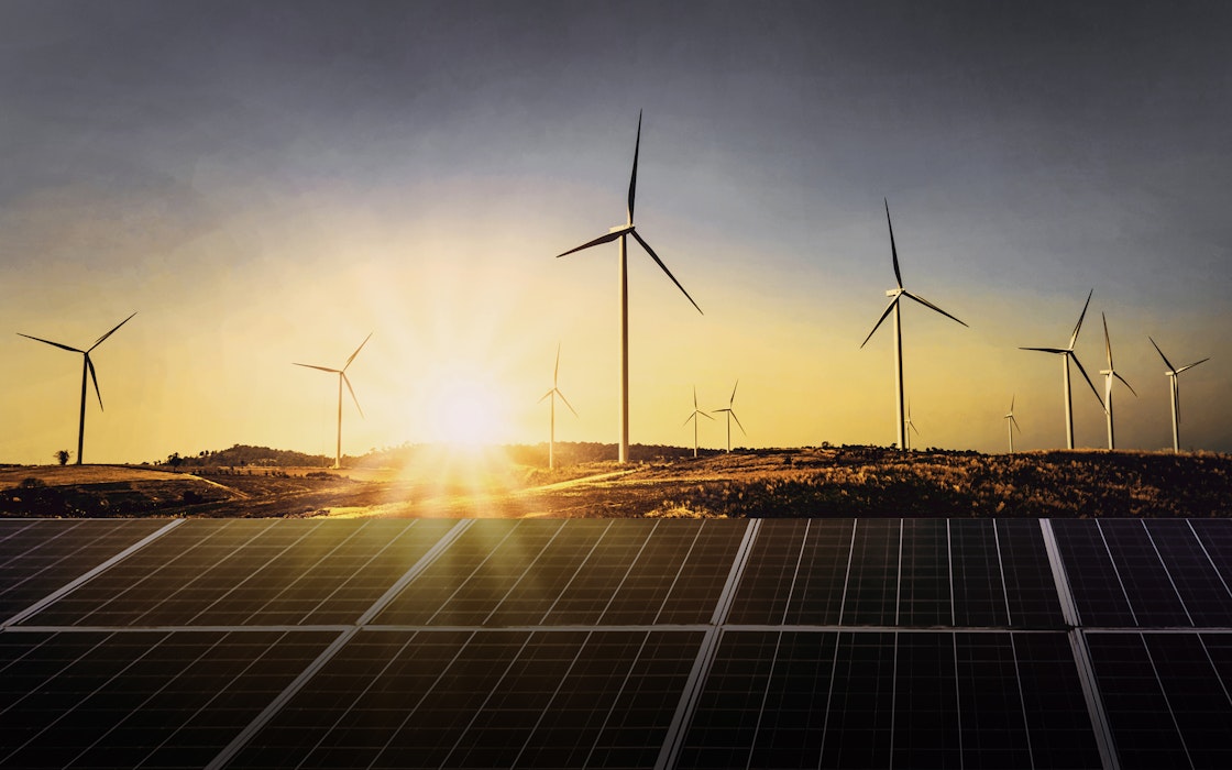 Hinter einer Solaranlage sieht im einen Sonnenuntergang und Windräder. Legen auch Sie Ihr Geld richtig an und sparen Sie in Selten Erden mit Golden Gates.