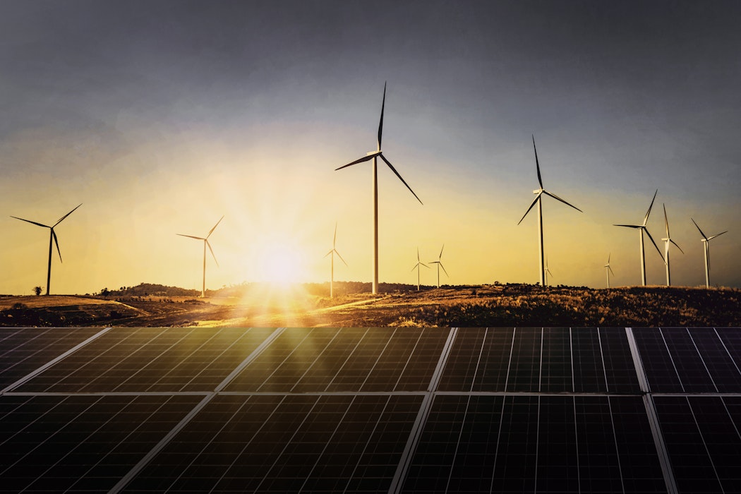 Hinter einer Solaranlage sieht im einen Sonnenuntergang und Windräder. Legen auch Sie Ihr Geld richtig an und sparen Sie in Selten Erden mit Golden Gates.