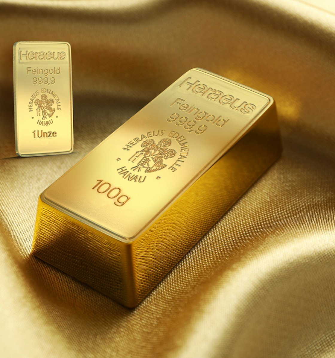 Auf einem goldenen Seidenstoff liegen ein 100g und ein 1 Unze Goldbarren. Sparen auch Sie in Gold mit den Sparplänen von Golden Gates.
