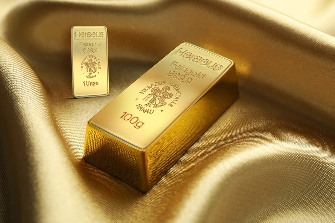 Auf einem goldenen Seidenstoff liegen ein 100g und ein 1 Unze Goldbarren. Sparen auch Sie in Gold mit den Sparplänen von Golden Gates.