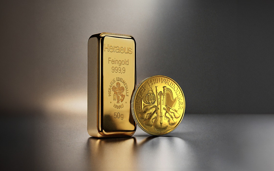 Vor einem dunklen Hintergrund stehen ein Goldbarren und eine Wiener Philharmoniker Goldmünze. Edelmetall-Sparpläne von Golden Gates.
