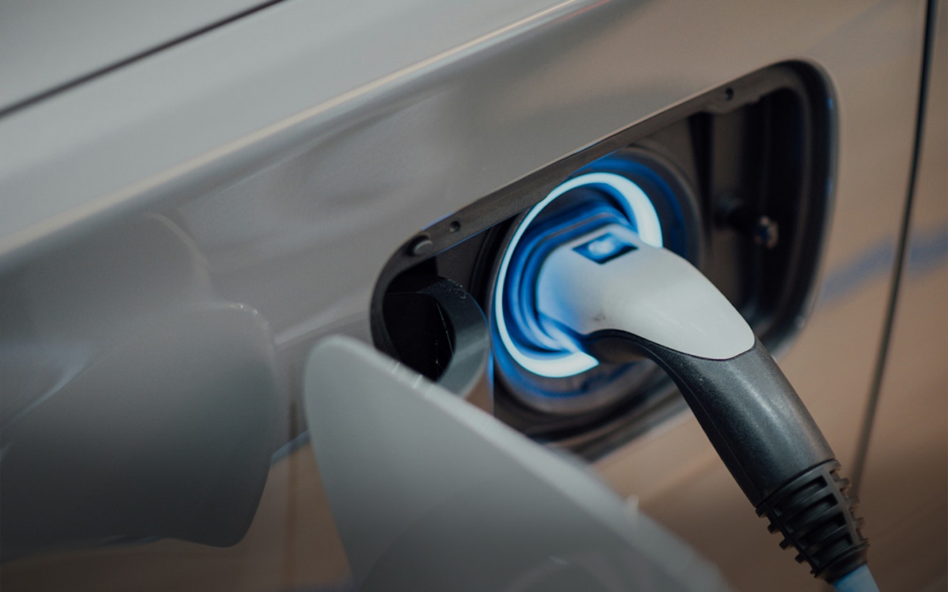 Automobil- und Energietechnik Auf diesem Bild ist der Ausschnitt eines Autos an der Ladesäule zu sehen. In Anlagemetalle sparen mit den Sparplänen von Golden Gates.