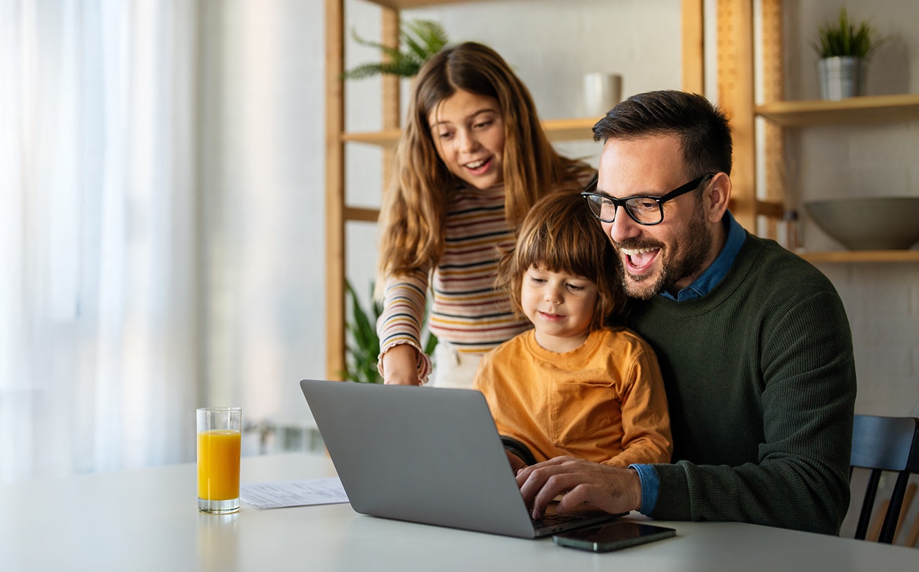 Eine junge Familie sitzt entspannt zusammen am Tisch und recherchiert auf einem Laptop. Sie prüfen Informationen zu Edelmetallanlagen, um ihre finanzielle Zukunft abzusichern. Mit einem sicheren Gefühl investieren sie in wertbeständige Edelmetalle, um sorglos in die Zukunft zu blicken.