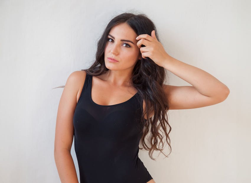 woman in black tanktop moving her hair away from her face