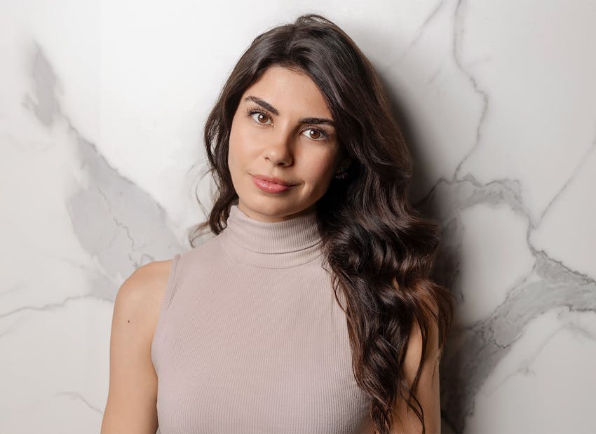 woman leaning against wall with her hair on one shoulder