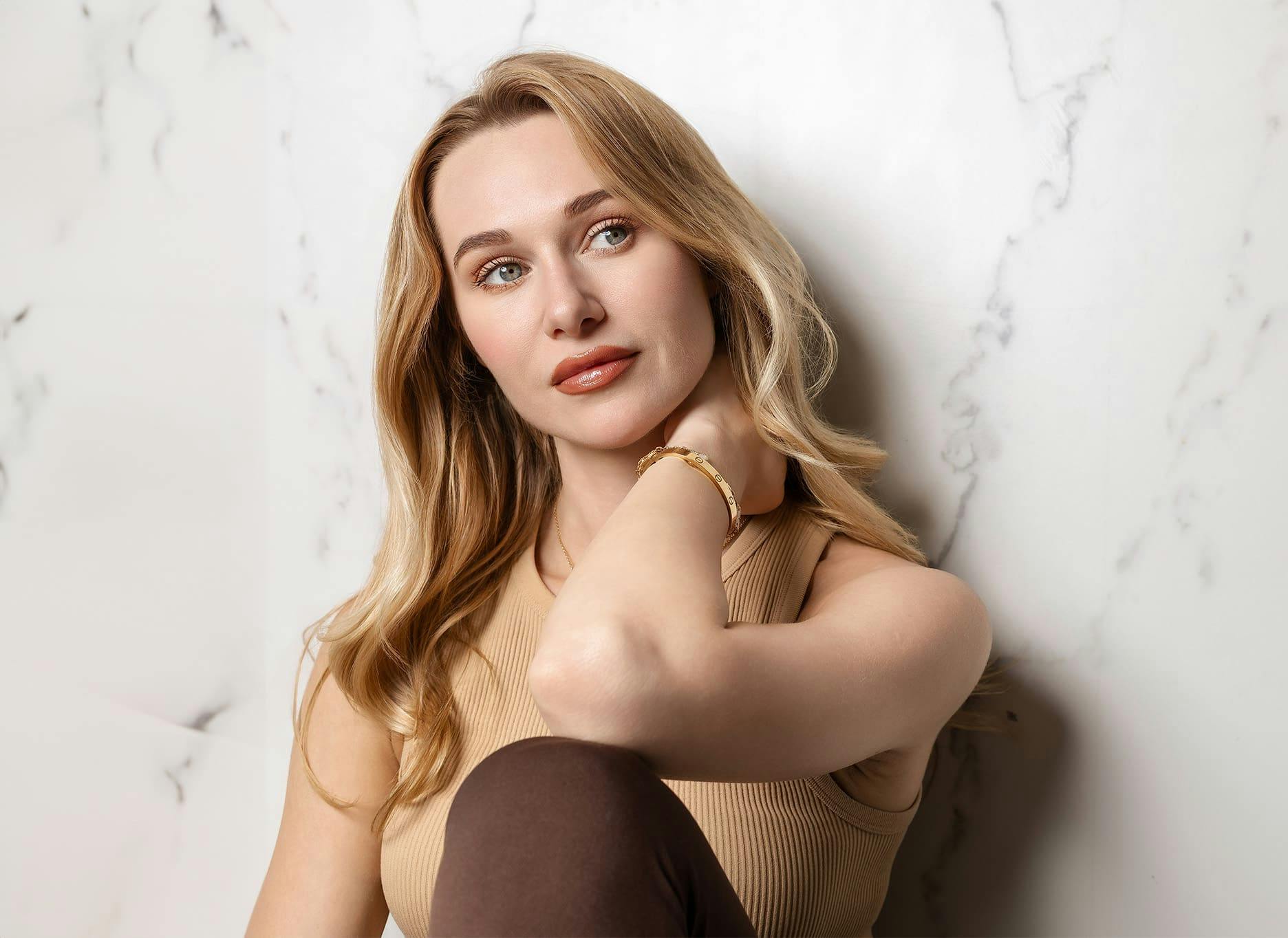 woman leaning against wall with her hand rubbing her neck