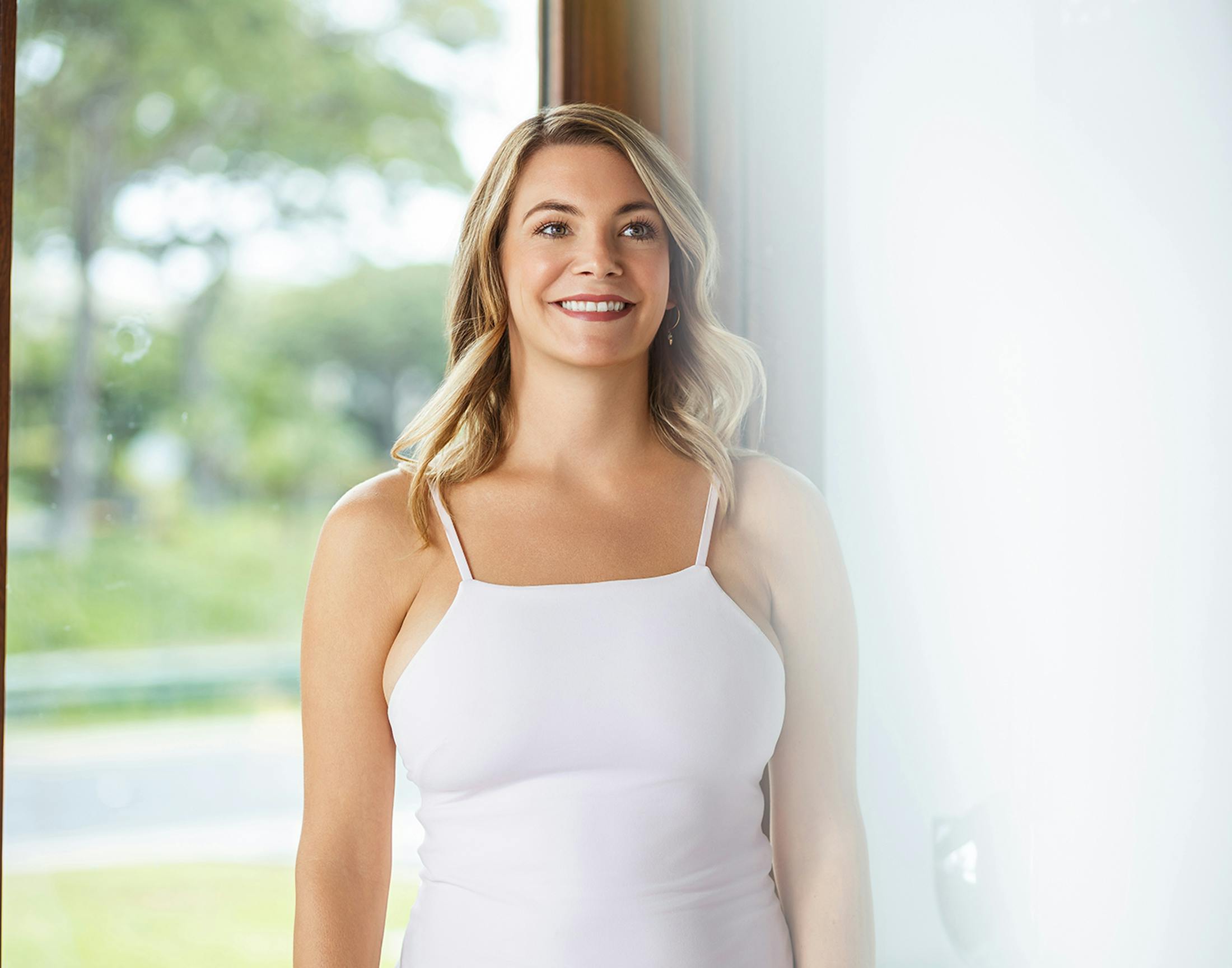 Woman smiling in front of a window