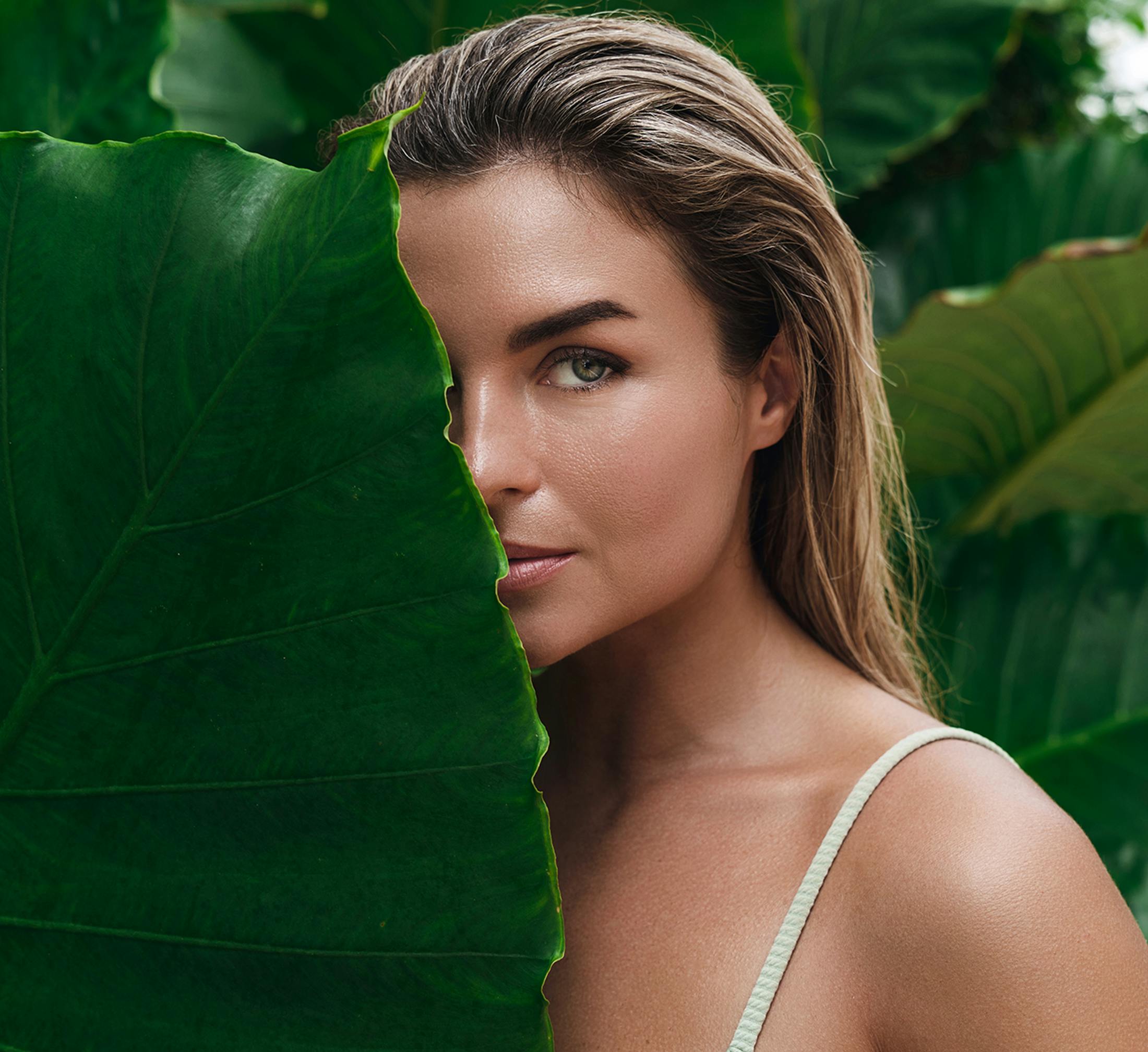 Woman with half her face behind a leaf