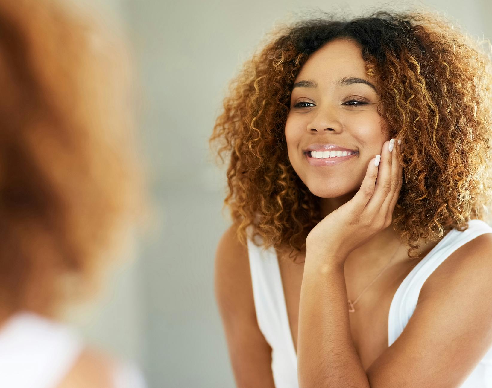 woman smiling into a mirror