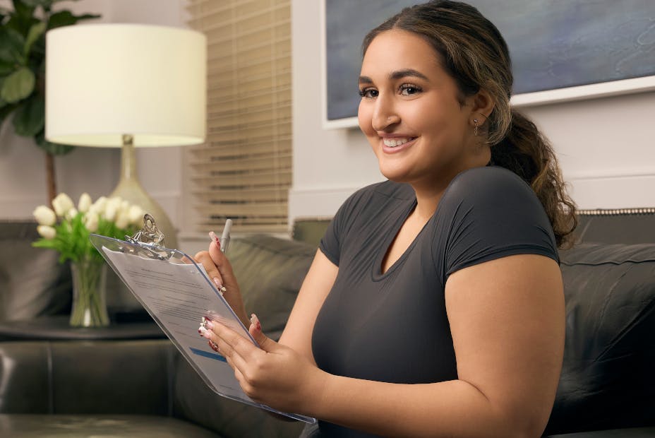 woman smiling holding clipboard'