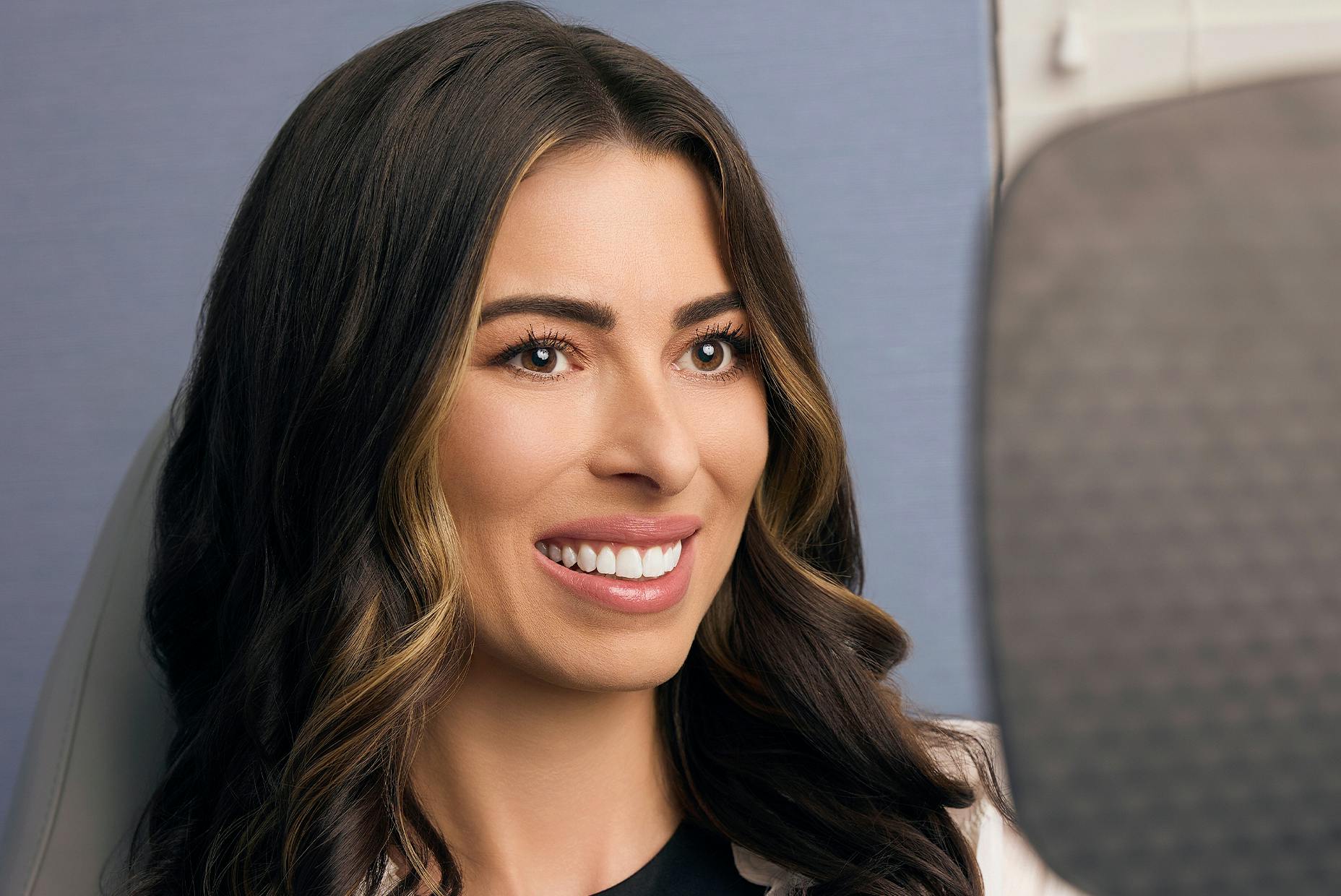 woman smiling while looking in a hand mirror