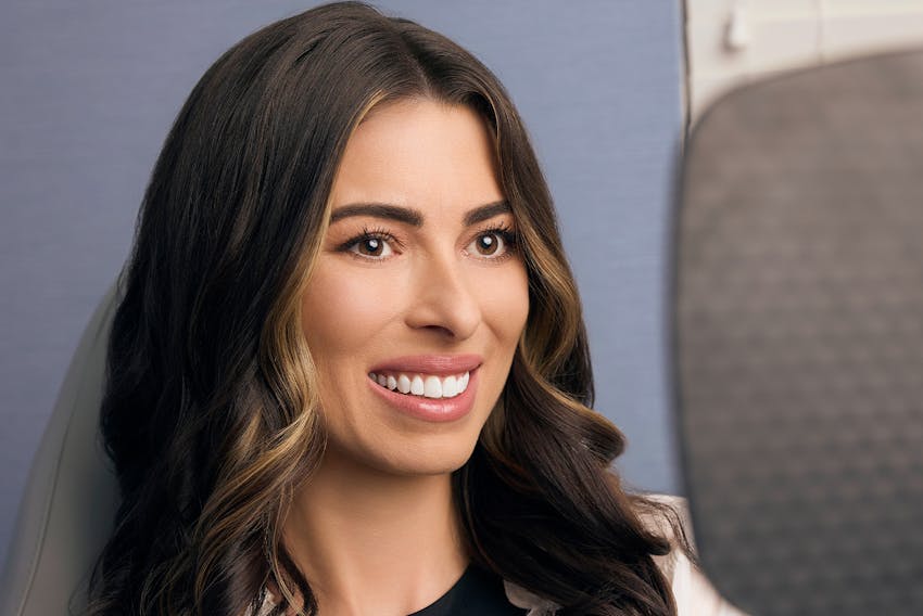 woman smiling while looking in a hand mirror