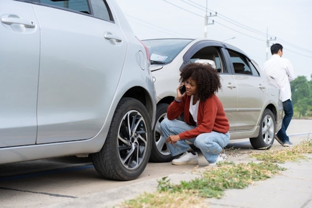calling Car Accident Attorney in North Charleston woman on the phone looking at the damage to their car after crash