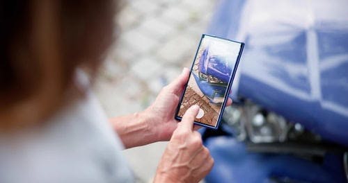 person taking a picture of the damage to their car