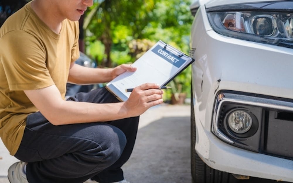 insurance adjuster reviewing damages someone logging the damage to their car