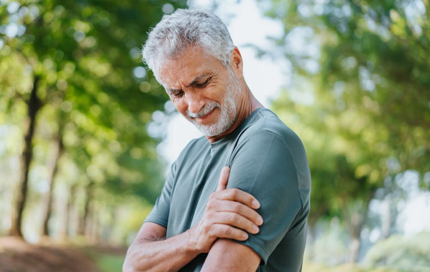 older man holding his shoulder in pain