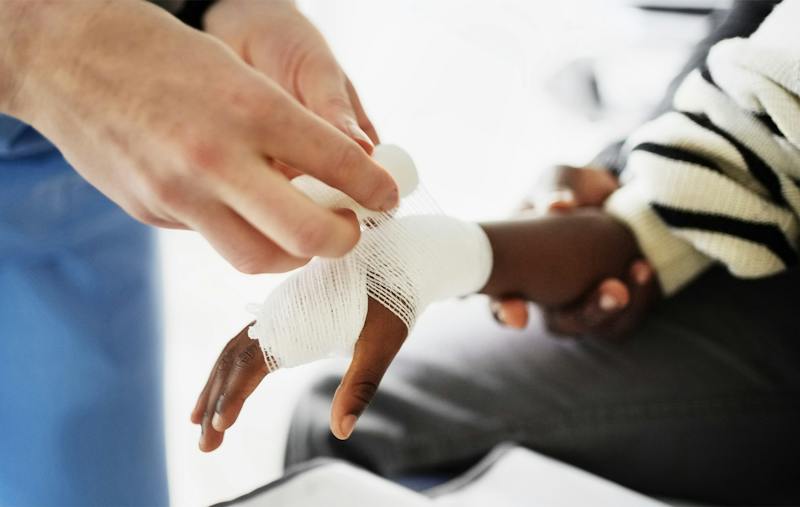 child getting their hand wrapped in gauze