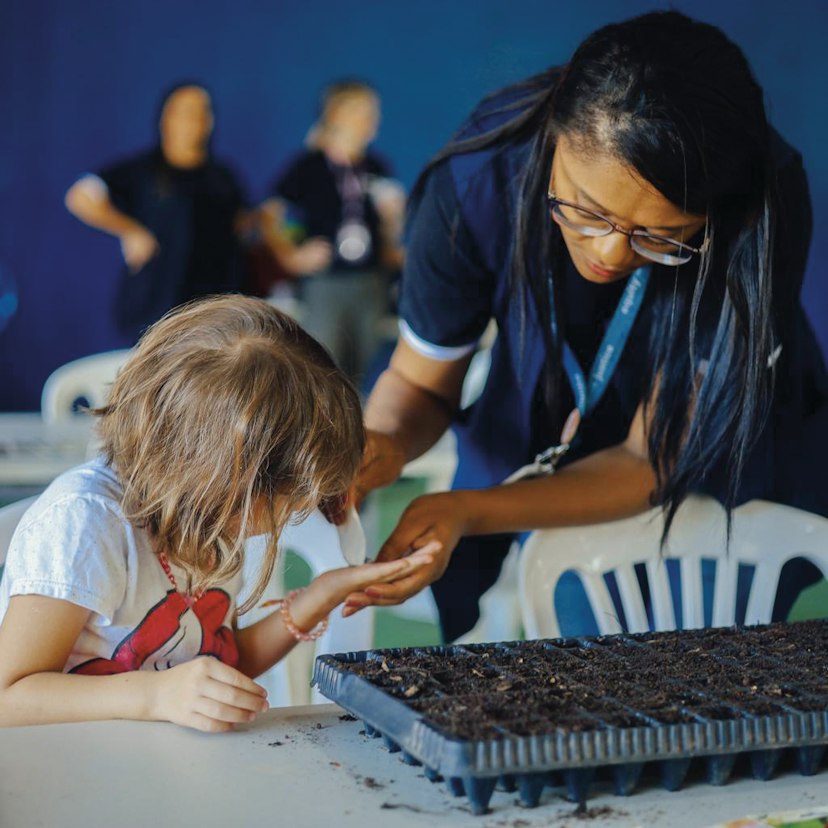 Student and teacher planting seeds, Brazil