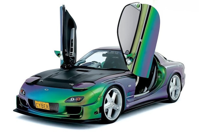 Green and purple chameleon painted Mazda RX-7 FD with vertical scissor doors open, white wheels, and CYBER license plate on white background