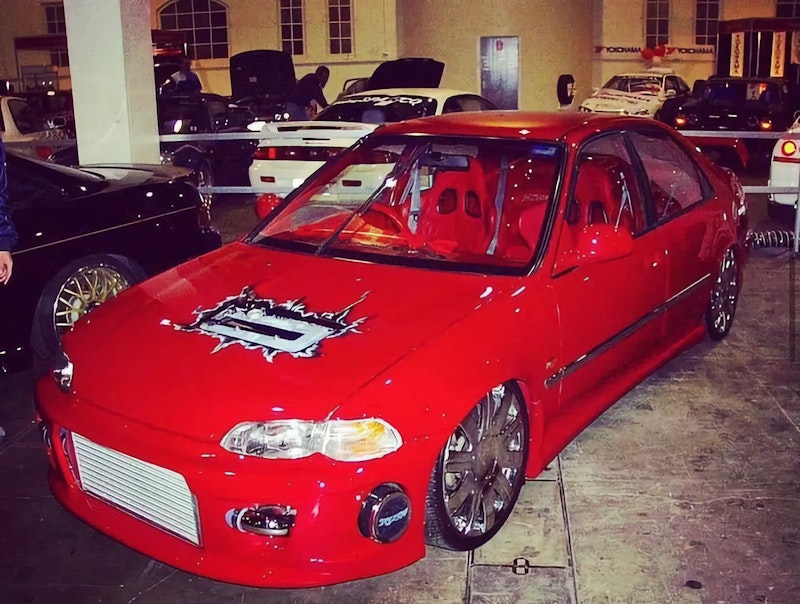 Red Honda Civic with airbrushed hood art and chrome wheels