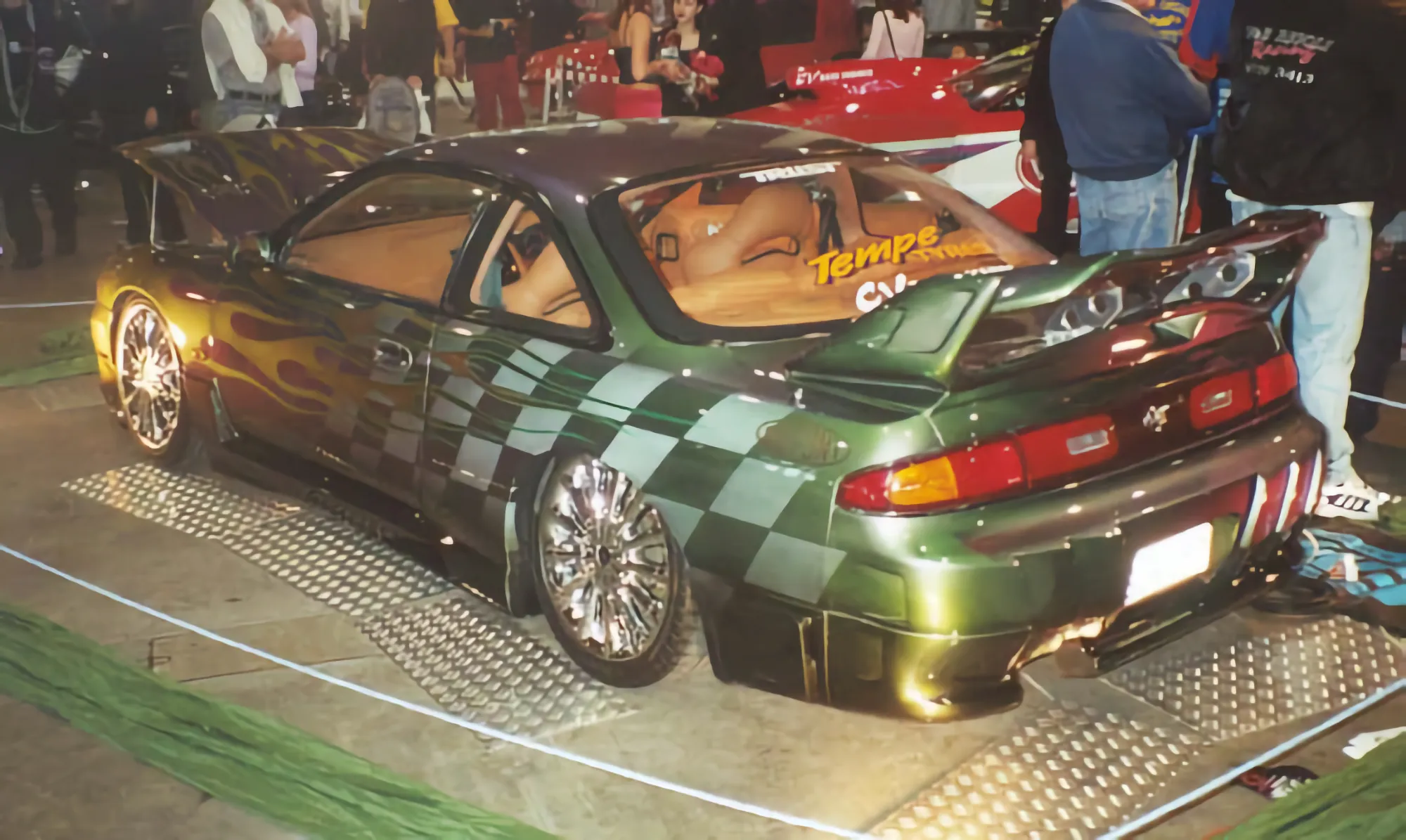 Custom green 200SX with checkerboard and flame paintwork on display at an indoor car show