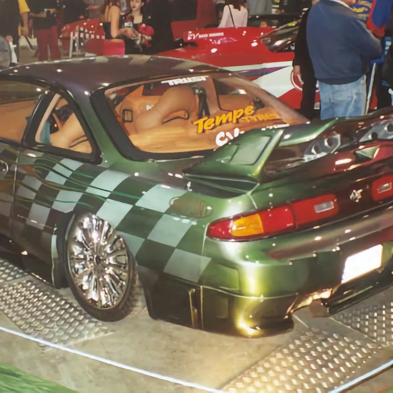 Custom green 200SX with checkerboard and flame paintwork on display at an indoor car show