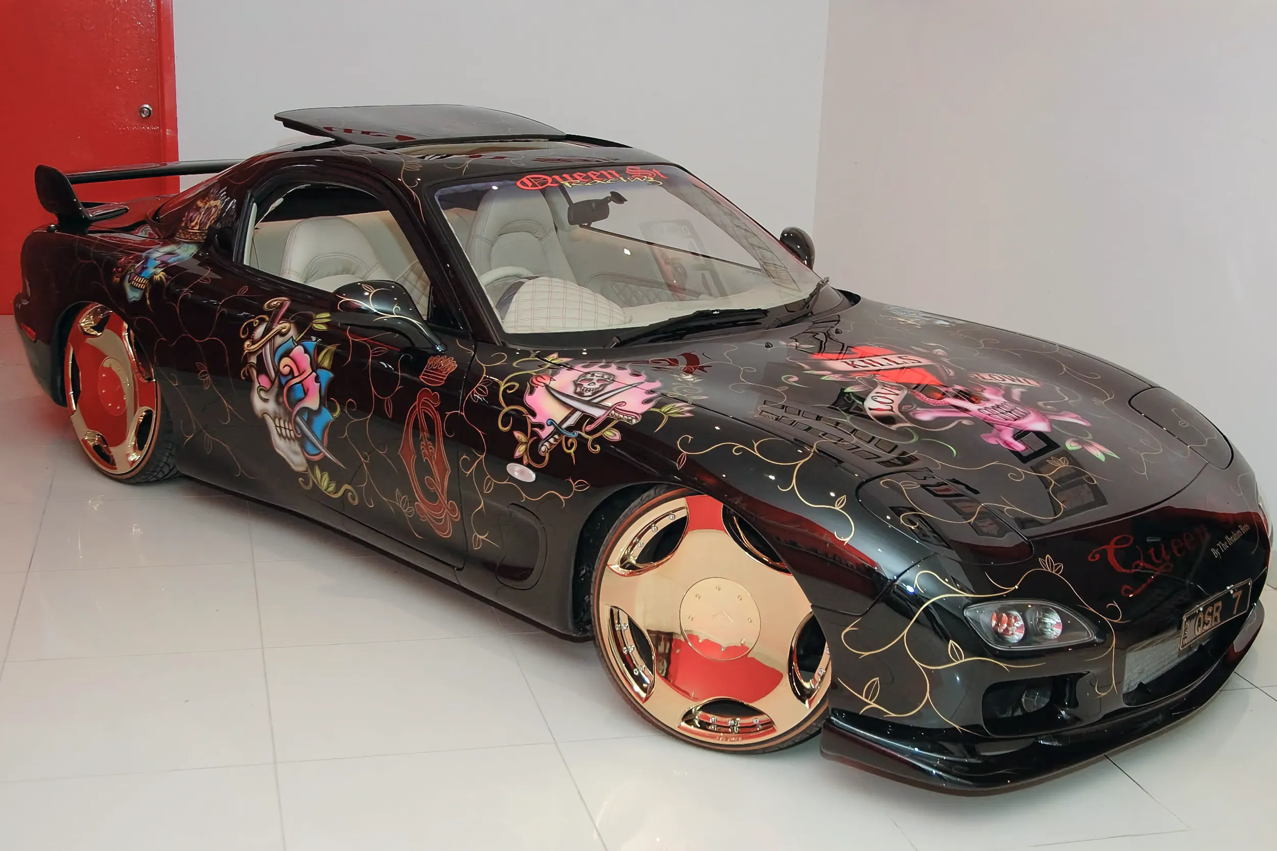Black RX7 with gold wheels, displayed indoors.