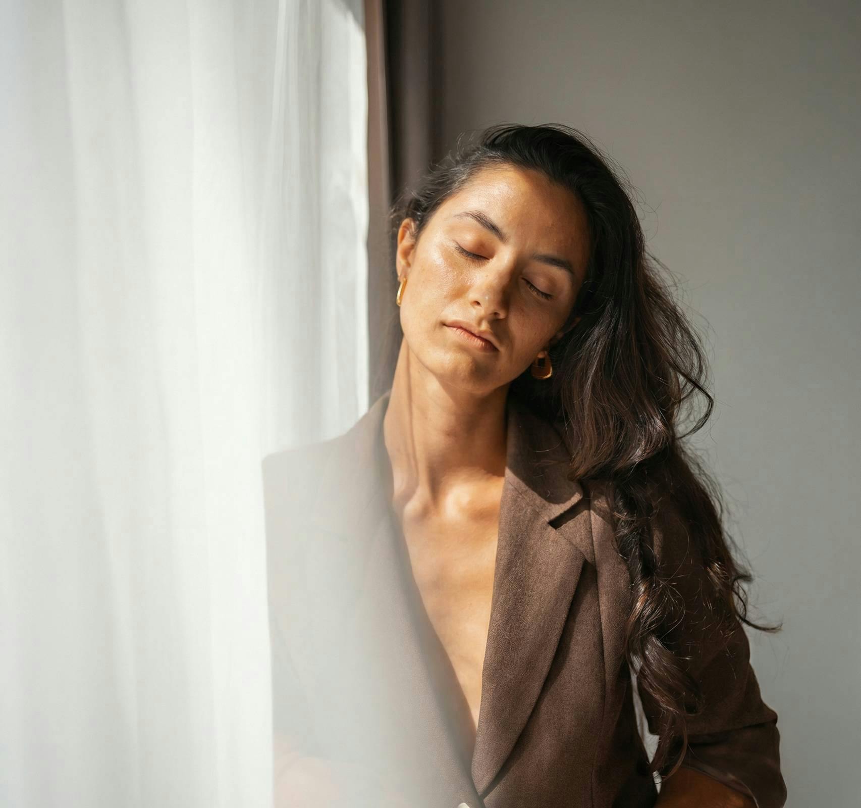 woman with eyes closed leaning against a window